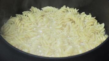 pasta cucinando su nero casseruola. tradizionale italiano cucina spaghetti bollito nel bollente acqua nel pentola. avvicinamento Visualizza di cucinando cibo nel padella video