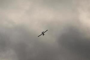 pequeño avión volador en el cielo en contra oscuro nubes foto