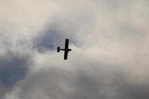 pequeño avión volador en el cielo en contra oscuro nubes foto