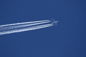 un avión y estelas de vapor en el cielo foto