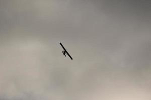 pequeño avión volador en el cielo en contra oscuro nubes foto