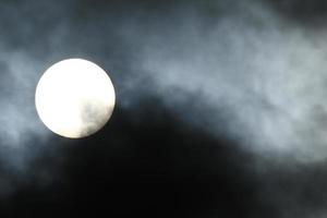 Sun disk behind backlit clouds photo