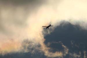 pequeño avión volador en el cielo en contra oscuro nubes foto