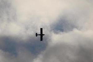 pequeño avión volador en el cielo en contra oscuro nubes foto