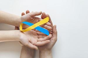 azul amarillo conciencia cinta en Ayudar mano para mundo abajo síndrome día wdsd marzo 21 levantamiento apoyo en paciente con abajo síndrome enfermedad invalidez y torácico toma de corriente síndrome foto