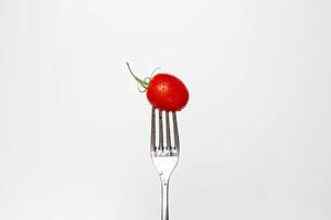 Photo of a fresh cherry tomato on a fork isolated on a white background, part of a series.