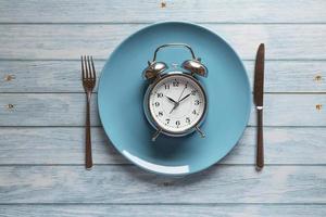 Meal planning for diet concept, Intermittent fasting concept with clock on plate, fork and knife on wooden table, Clock on plate with fork and knife, intermittent fasting, meal plan, weight loss photo