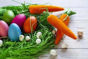 Happy Easter. Congratulatory easter background. Colorful Easter eggs in a grass nest with carrots photo