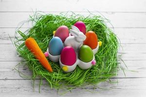 Banner.Easter eggs, carrot and a rabbit basket in a grass nest on a wooden background. The minimal concept of Easter. Top view. An Easter card with a copy of the place for the text. photo