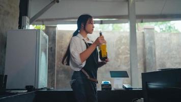 un asiatique femme qui est nettoyage en haut une désordonné cuisine dans une café video