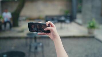 hand- Holding een slim telefoon terwijl nemen een selfie van een groep van Dames video