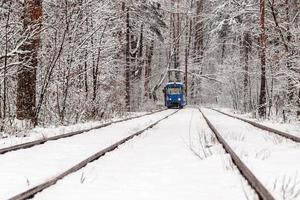 An old tram moving through a winter forest photo