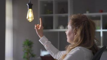 Idea lamp. Mature business woman thinks about idea and idea lamp flashes. The lamp that illuminates the idea of a mature business woman . video