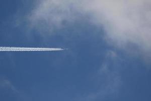 un avión y estelas de vapor en el cielo foto