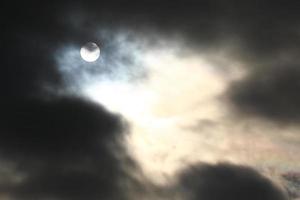 Sun disk behind backlit clouds photo