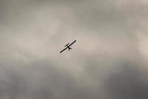 pequeño avión volador en el cielo en contra oscuro nubes foto