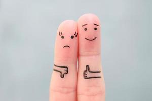 Fingers art of couple. Woman showing thumb down and man showing thumb up. Concept of disagreement in family. photo