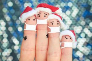 Fingers art of family in medical mask from COVID-2019 celebrates Christmas. Concept of people in New Year hats. photo