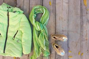 Children's autumn clothes and yellow leaves on old wooden background. Top view. Flat lay. photo