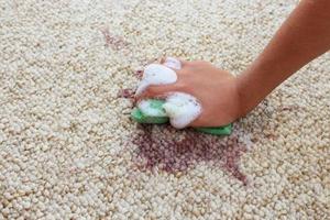 hembra mano limpia el alfombra con un esponja y detergente. foto