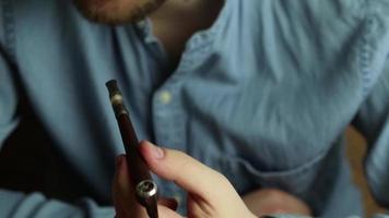 homme avec une barbe jouit fumeur réel le tabac. hoche la tête avec approbation. en utilisant fumeur tuyau video