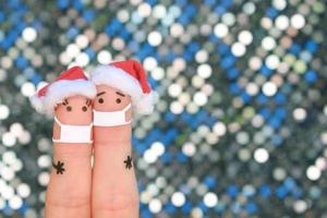 dedos Arte de Pareja en médico máscara desde covid-2019 celebra Navidad. concepto de personas en nuevo año sombreros. foto