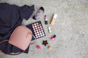 Summer women's clothing dress, cosmetics, sunglasses, handbag on stone background. Top view. Flat lay. photo