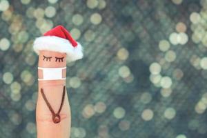 Finger art of lonely woman in medical mask from COVID-2019. Concept people celebrate Christmas in new year hat. Toned image. photo