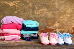 Baby shoes, clothing and pacifiers pink and blue on the old wooden background. photo