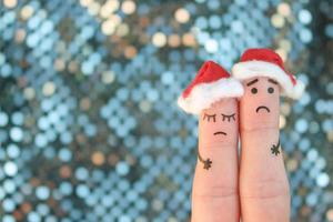 Fingers art of displeased couple celebrates Christmas. Concept of sad man and woman in new year hats. photo