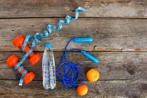 Sports equipment, water and tangerines on old wooden background. Top view photo