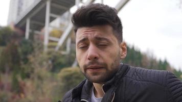 The sad young man in the city center is waiting in the cold. The unhappy young man stands in the city center in the autumn season and looks around. video