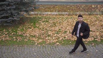 el hombre caminando en el ciudad en el otoño estación. el hombre caminando en el la carretera con amarillo seco hojas en el piso es considerado. video