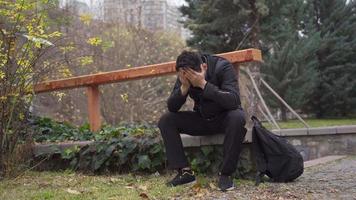 le triste homme séance en plein air, famille problèmes, le concept de la dépression et suicide. le Jeune homme séance sur le sol en plein air devient émotif et regards à le ciel par dépression. video