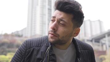 Close-up of thoughtful unhappy young man on the street. The man in the city center is thoughtful and helpless about his unhappiness. video