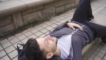 jong Mens resting buitenshuis, vinden vrede, attent en gelukkig. jong Mens aan het liegen Aan de grond buitenshuis op zoek Bij de lucht, dromen, hopend, vinden vrede. video