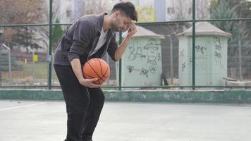 agresivo joven hombre consiguiendo enojado. neurosis. el hombre molesto a jugar baloncesto a pacificar su enojo. ira gestión. histerismo. video