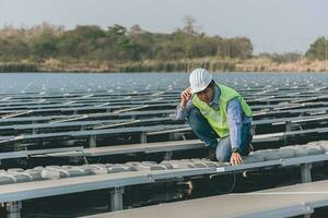 Engineer inspector holding laptop and working in solar panels power plant checking photovoltaic cells and electricity production. photo