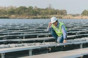 Engineer inspector holding laptop and working in solar panels power plant checking photovoltaic cells and electricity production. photo