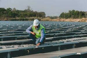 Engineer inspector holding laptop and working in solar panels power plant checking photovoltaic cells and electricity production. photo