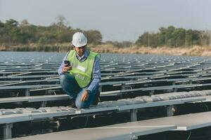 Engineer inspector holding laptop and working in solar panels power plant checking photovoltaic cells and electricity production. photo