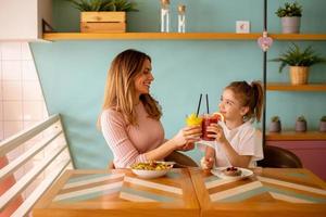 Mother and daughter having a breakfast with fresh squeezed juices in the cafe photo