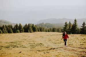 Young woman walking with backpack over green hills photo