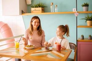 Mother and daughter having a breakfast with fresh squeezed juices in the cafe photo