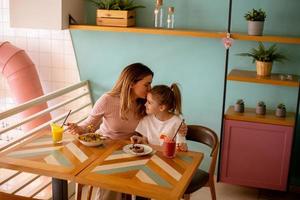 madre y hija teniendo un desayuno con Fresco exprimido jugos en el café foto