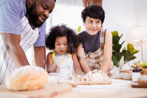 Happy African American family enjoy together while prepare the flour for making cookies at home photo