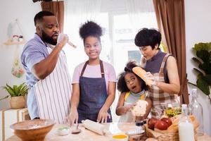 contento africano americano familia disfrutar juntos mientras preparar el harina para haciendo galletas a hogar foto