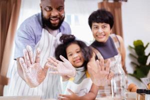 Happy African American family enjoy together while prepare the flour for making cookies at home photo