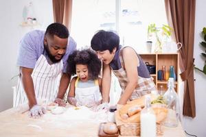 contento africano americano familia disfrutar juntos mientras preparar el harina para haciendo galletas a hogar foto