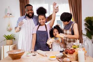 contento africano americano familia disfrutar juntos mientras preparar el harina para haciendo galletas a hogar foto